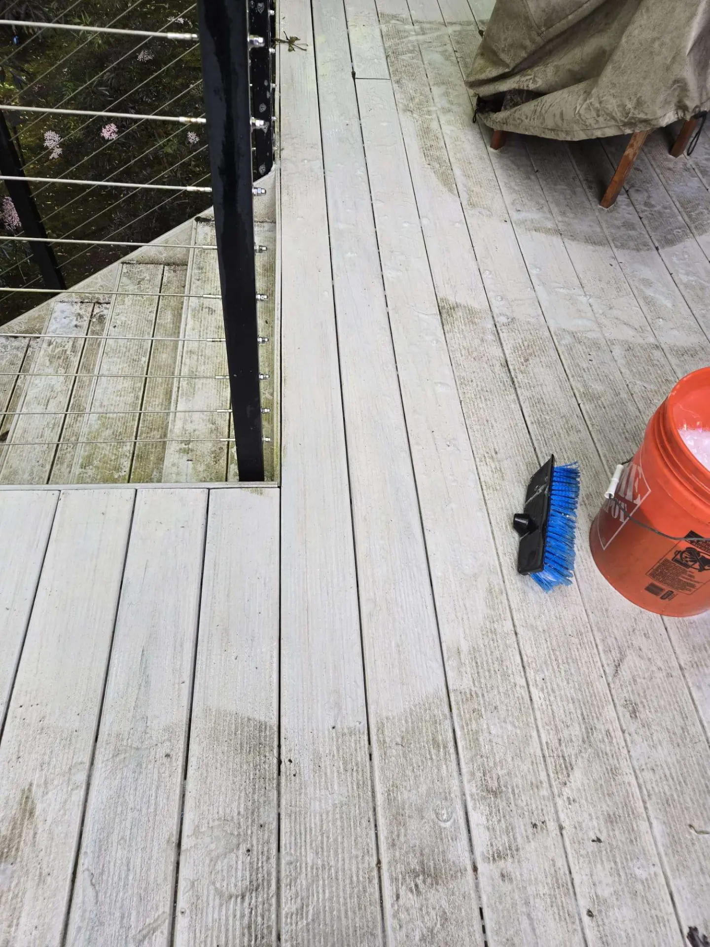 Wood deck being washed, with the cleaned section noticeably brighter